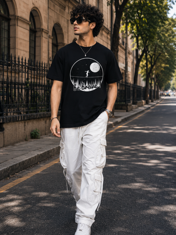 Male model wearing Zingleberry Be Brave Premium Black Cotton Graphic T-Shirt paired with white cargo trousers for a stylish casual streetwear look.
