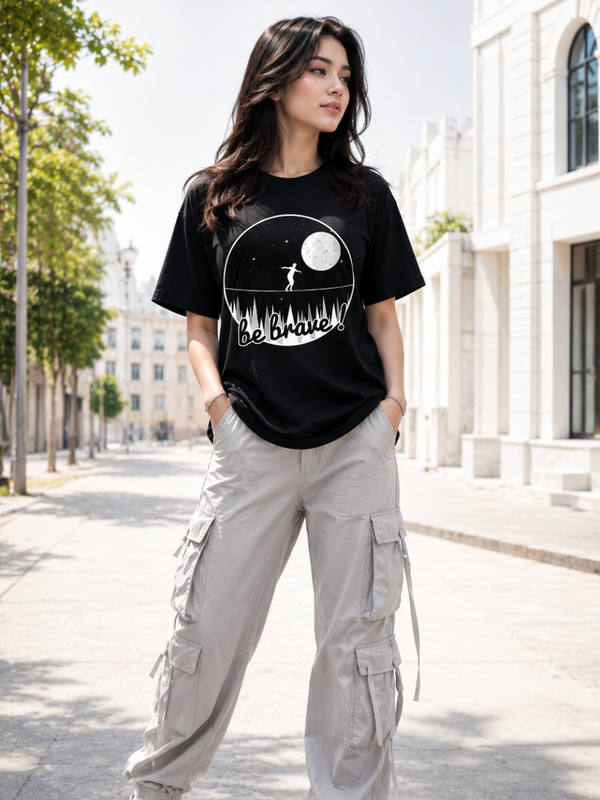 Female model wearing Zingleberry Be Brave Premium Unisex Black Cotton Graphic T-Shirt styled with light cargo pants for a modern summer streetwear outfit.