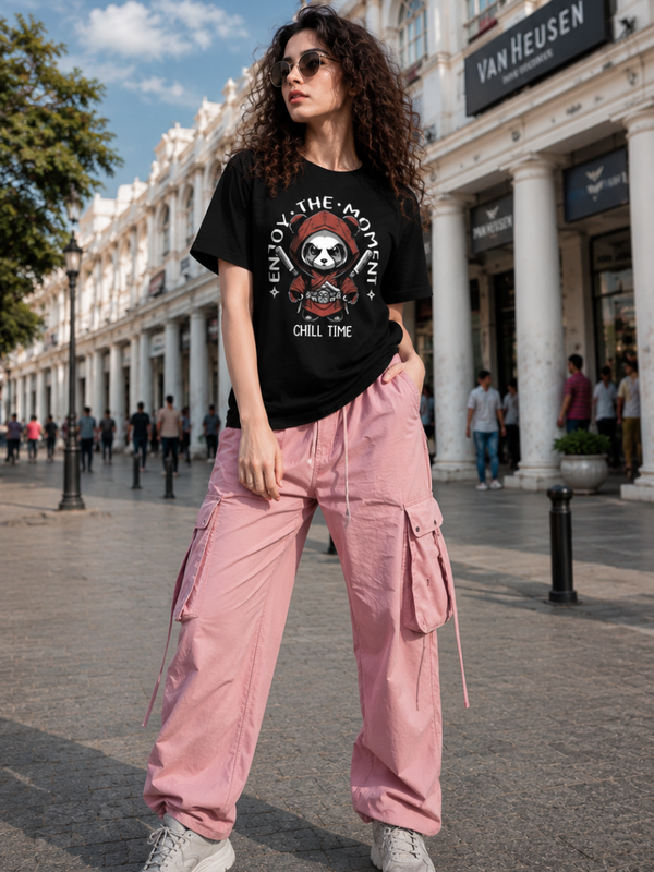 Female model wearing Zingleberry Enjoy The Moment Panda Premium Unisex Black Cotton Graphic T-Shirt styled with pink cargo pants for a trendy summer streetwear outfit.