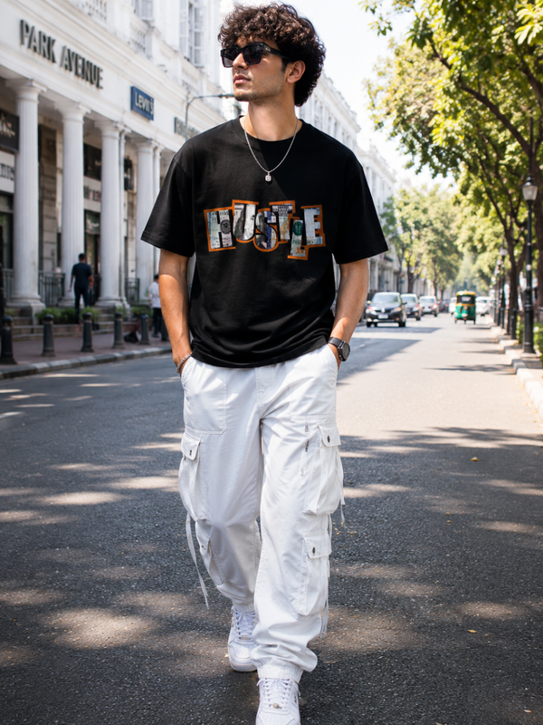 Male model wearing Zingleberry Hustle Premium Black Cotton Graphic T-Shirt paired with white cargo pants for a modern urban streetwear look.
