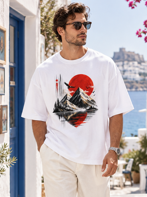 Male model wearing Zingleberry white oversized Red Sun Mountain landscape graphic T-shirt with off-white trousers.