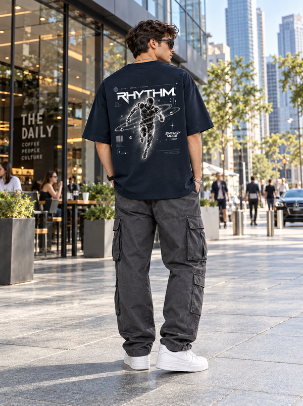 Male model showing RHYTHM Energy Mode futuristic runner back artwork on Zingleberry black oversized T-shirt with grey cargo trousers