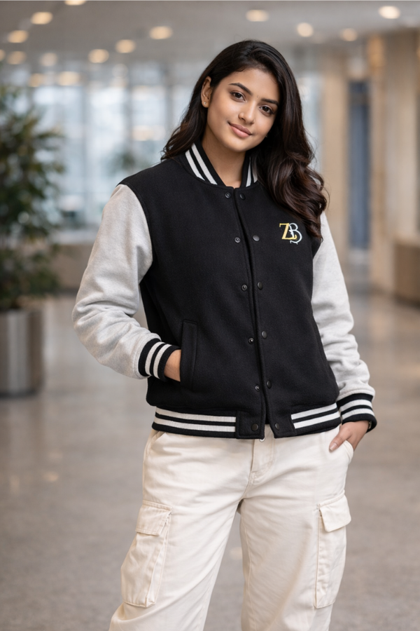 A woman modeling the Zingleberry black varsity jacket with off-white sleeves, paired with white cargo pants for a modern urban fashion look.