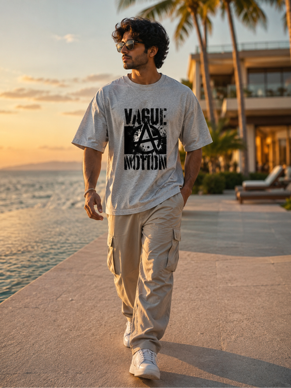 Male model with zingleberyy's oversized unisex Vague motion printed tshirt walking by a waterfront with palm trees and a building in the background