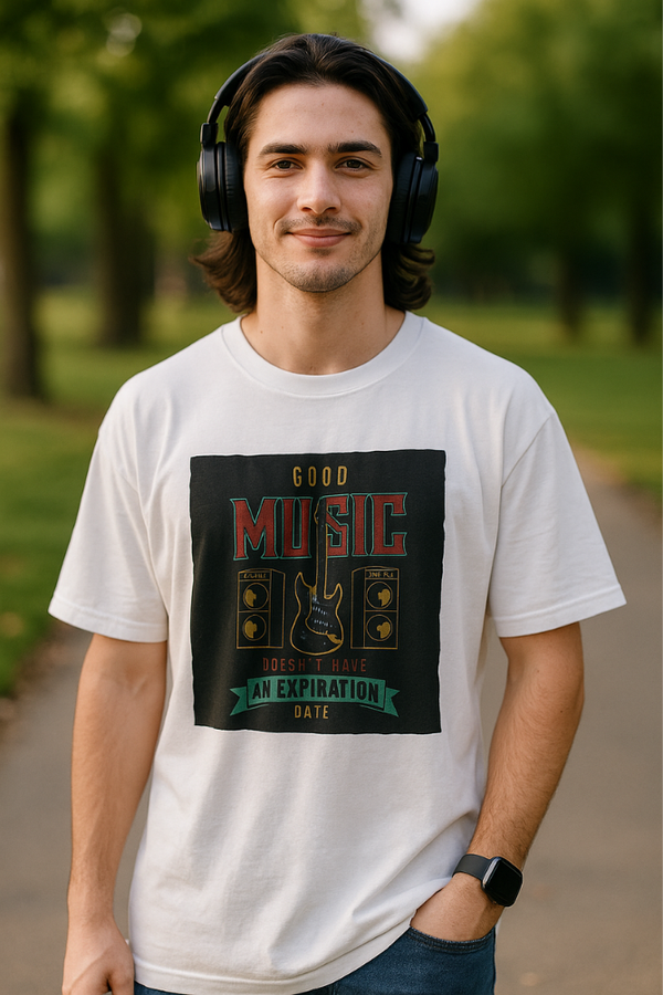 Young man wearing Zingleberry’s unisex oversized white t-shirt with 'Good Music Doesn’t Have an Expiration Date' vintage guitar print, styled with headphones in a park.