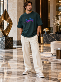 Male model wearing Zingleberry petrol blue premium unisex oversized T-shirt with neon-gradient Zingleberry logo, cream relaxed-fit trousers and sneakers in luxury setting