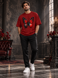Male model wearing Zingleberry Crimson Nocturne red unisex oversized Gothic butterfly T-shirt styled with black trousers and white sneakers.