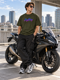 Male model wearing Zingleberry olive green premium unisex oversized T-shirt with neon-gradient Zingleberry signature logo, black cargo trousers and sneakers beside a black sports motorcycle