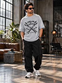 Male model wearing Zingleberry Fuelled by Freedom grey unisex oversized mechanic T-shirt with black cargo trousers and white sneakers.
