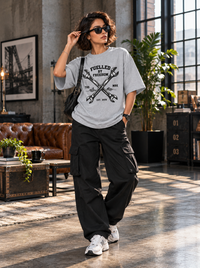 Female model wearing Zingleberry Fuelled by Freedom grey oversized mechanic graphic T-shirt with black cargo pants and white sneakers.