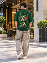 Man wearing Zingleberry Grow Through It unisex oversized T-shirt with large botanical sculpture and red hibiscus back graphic.