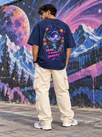 Male model showing large Home in Another Universe cosmic heart back artwork on Zingleberry navy blue oversized T-shirt with cream cargo trousers