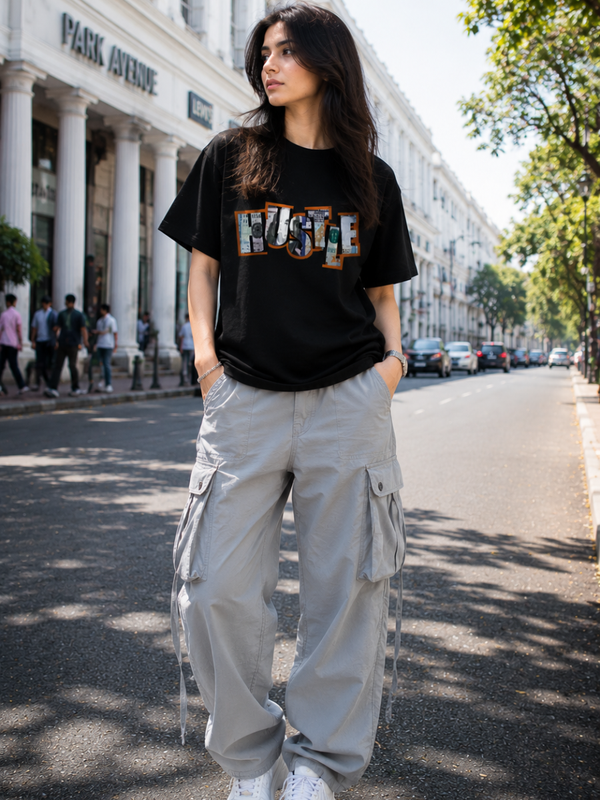 Female model wearing Zingleberry Hustle Premium Unisex Black Cotton Graphic T-Shirt styled with light grey cargo pants for a fashionable summer streetwear outfit.