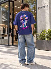 Male model showing colourful Just A Dream surreal fantasy back artwork on Zingleberry navy blue oversized T-shirt with relaxed light-blue denim jeans