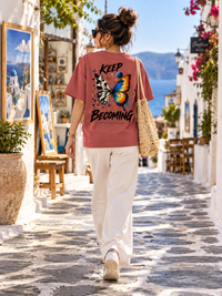 Woman wearing Zingleberry Keep Becoming brick-red oversized T-shirt with colourful butterfly statement back print.