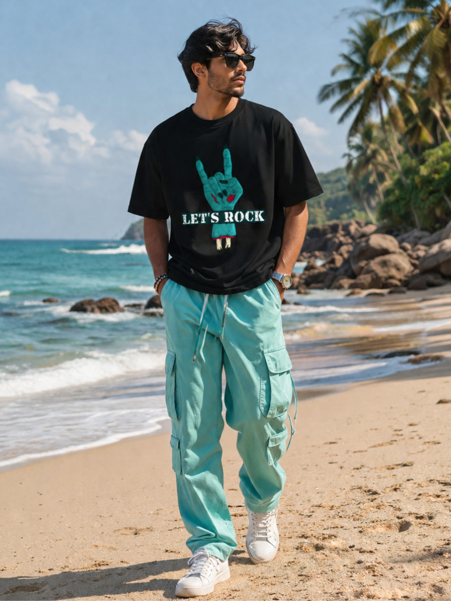 Male model wearing Zingleberry Let's Rock Premium Unisex Black Cotton Graphic T-Shirt with turquoise cargo pants for a stylish summer streetwear look.