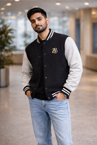 A man wearing the Zingleberry black and off-white unisex varsity jacket with light-wash denim jeans, showcasing a clean and casual aesthetic.