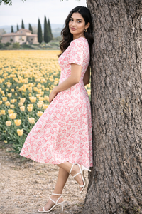 Model posing beside a tree in Zingleberry pink heart all-over print A-line midi dress styled for a premium outdoor photoshoot