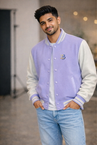 A man wearing Zingleberry's premium lilac and cream unisex varsity jacket with ZB chest logo, styled with light blue jeans for a modern streetwear look.