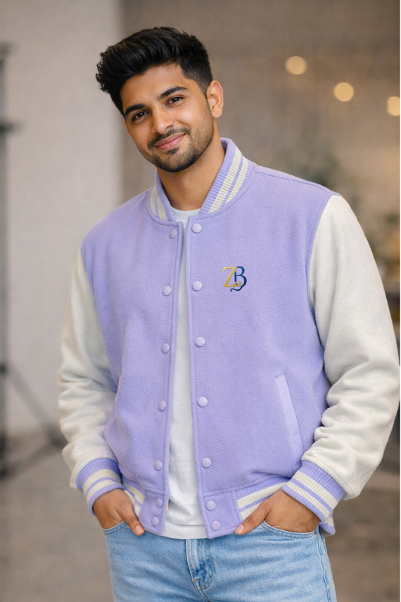 A man wearing Zingleberry's premium lilac and cream unisex varsity jacket with ZB chest logo, styled with light blue jeans for a modern streetwear look.