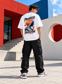 Male model wearing Zingleberry Progress Over Perfection white oversized T-shirt with large architectural motivational back graphic, black cargo trousers and sneakers.