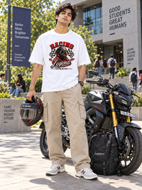 Male model wearing Zingleberry Racing Legend white oversized motorsport graphic T-shirt with beige cargo pants beside a motorcycle on a modern college campus.