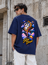 Back view of male model wearing Zingleberry Slow Down navy blue oversized graphic T-shirt with colourful cosmic clock artwork.