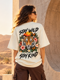 Female model wearing Zingleberry Stay Wild Stay Kind off-white oversized T-shirt featuring a large tiger and tropical floral back print.
