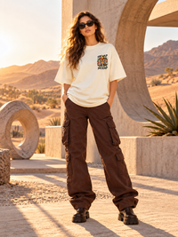 Female model wearing Zingleberry Stay Wild Stay Kind tiger graphic unisex oversized T-shirt in off white with brown cargo pants.