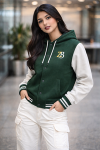 A woman modeling the Zingleberry Bottle green and off-white premium varsity hoodie jacket, styled with white cargo pants for an urban look.